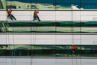 3 mænd hænger på bygning og vasker vinduer