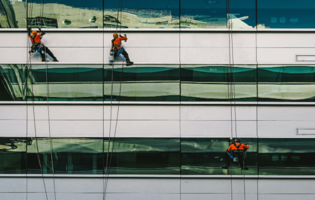 3 mænd hænger på bygning og vasker vinduer